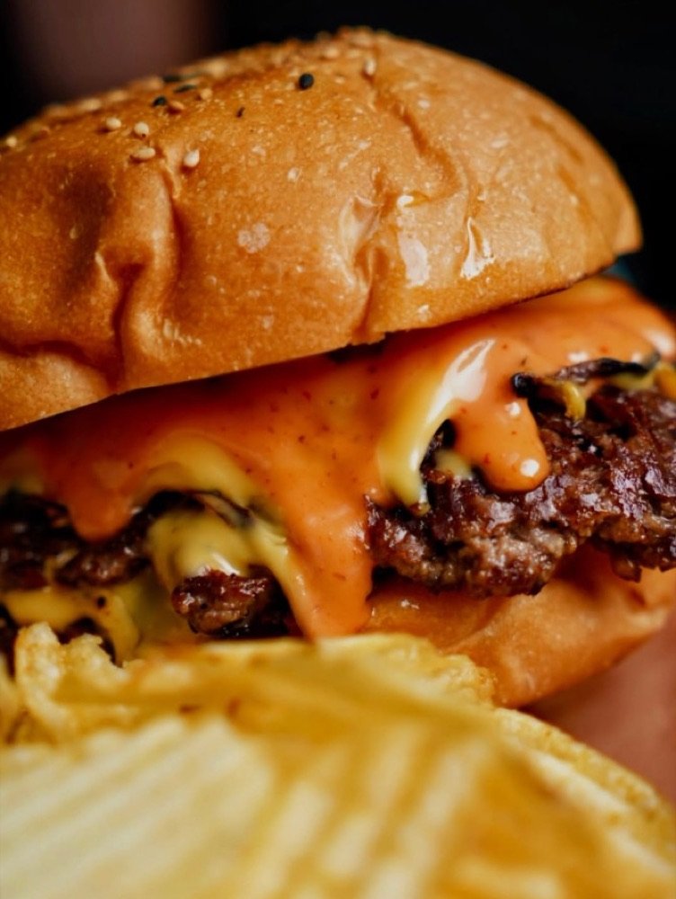 Smash burger de Wop's Comida Callejera con queso derretido y papas onduladas